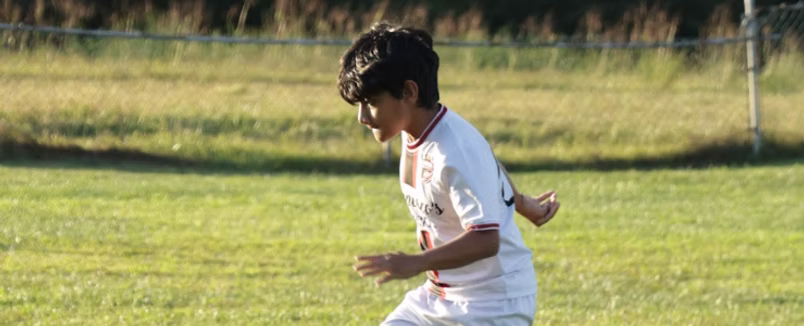 A young Gioca player running with the ball on the pitch