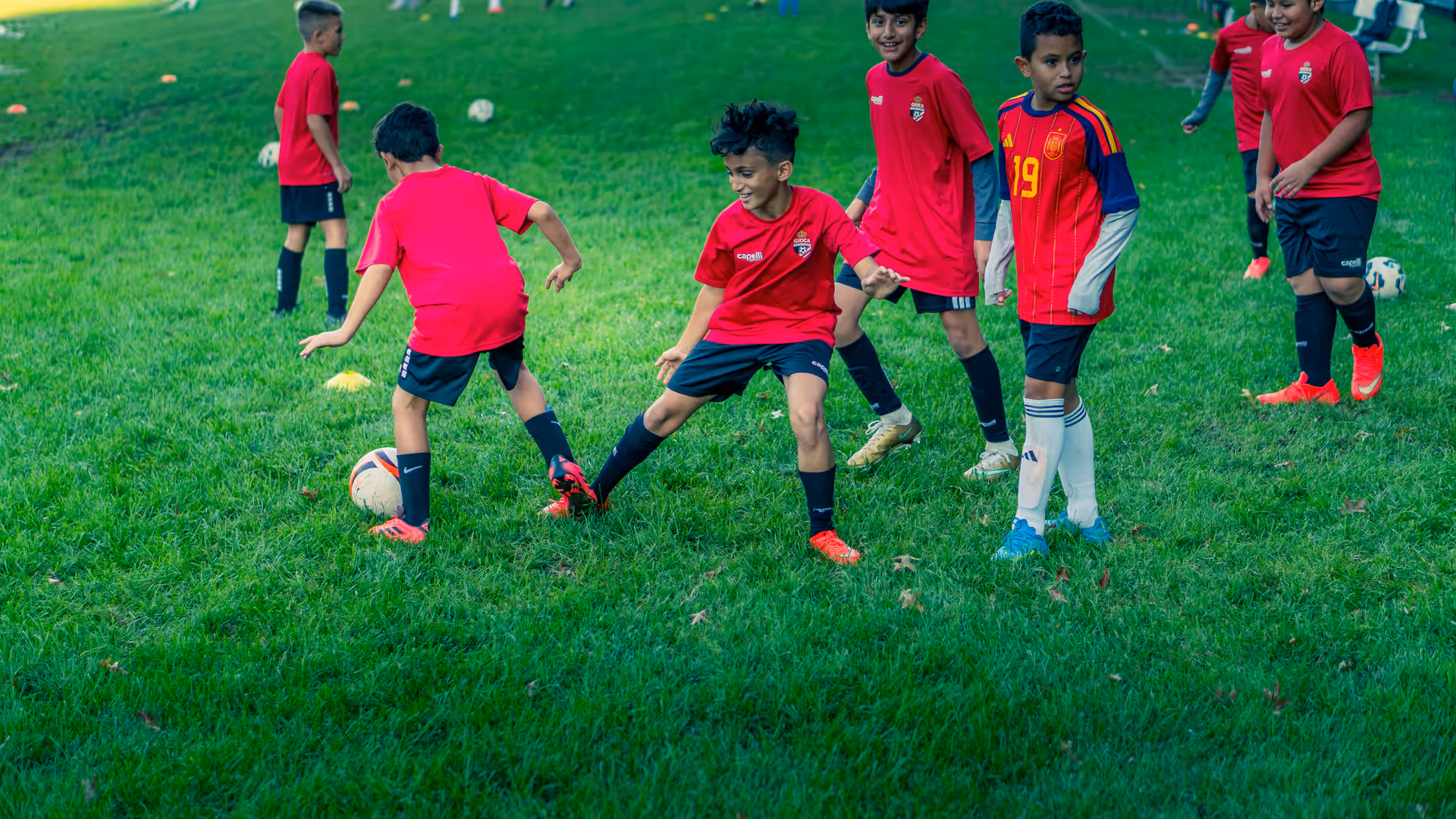 Young Gioca players smiling through a one-against-one duel at training