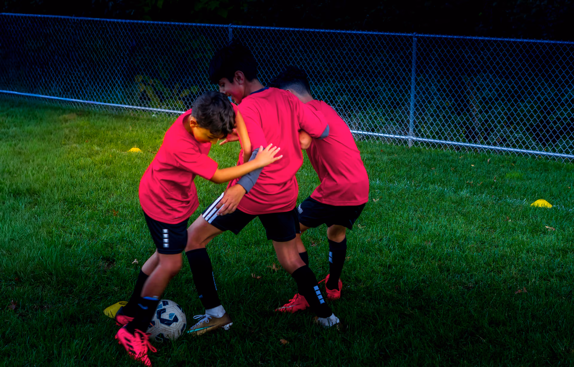 Three young players working in a tight shielding drill between yellow cones